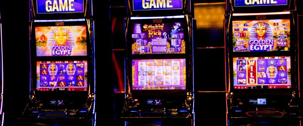 pexels-photo-29825627-29825627 Three illuminated slot machines in a bustling casino at night.